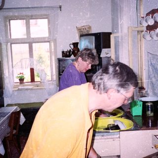 Two women in a kitchen during snowfall.