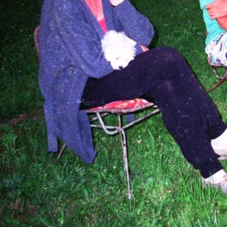 Three people sitting outdoors at night, relaxing.