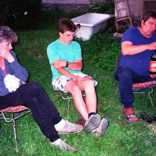 Three people sitting outdoors at night, relaxing.