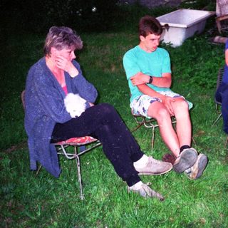 Three people sitting outdoors at night, relaxing.