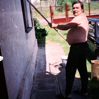 Man using a long pole to clean gutter.