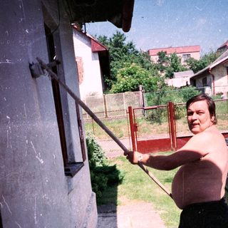 Man using a long pole to clean gutter.