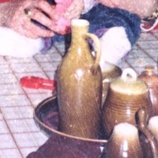 Woman holding baby at kitchen table with bottles.