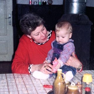 Woman holding baby at kitchen table with bottles.