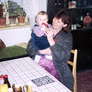 Woman holding child in vintage kitchen setting.