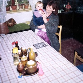 Woman holding child in vintage kitchen setting.