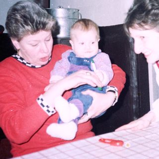 Two women holding and caring for a baby indoors.