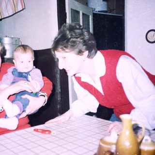 Two women holding and caring for a baby indoors.