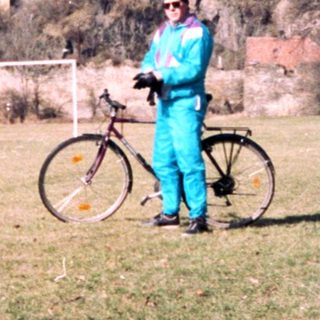 Person in cycling gear poses with bike near medieval ruins.