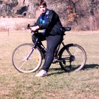 Person rides bicycle near medieval castle ruins.
