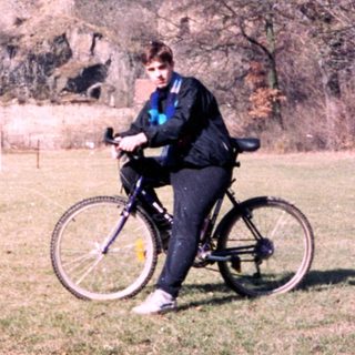 Person rides bicycle near medieval castle ruins.