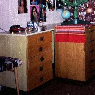 Christmas tree in cozy, cluttered room with photos.