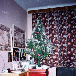 Vintage room with decorated Christmas tree, old furniture, and framed photos.