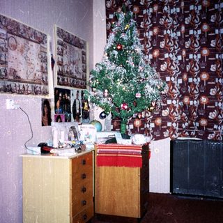 Vintage room with decorated Christmas tree, old furniture, and framed photos.