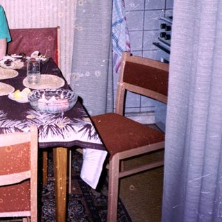 A person sitting at a home dining table with food.