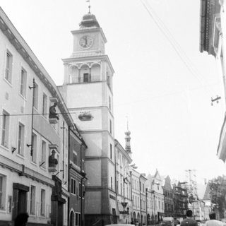 Historic European street with clock tower and vintage cars.