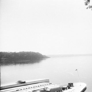 Scenic lake view with boat and misty hills.