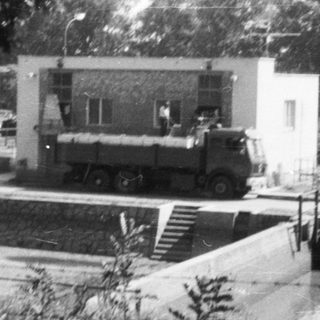 Military truck parked near building in outdoor area.