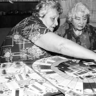 Two elderly women playing board game together.