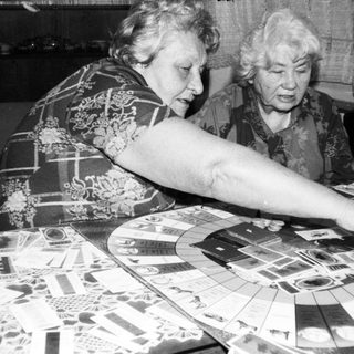 Two elderly women playing board game together.