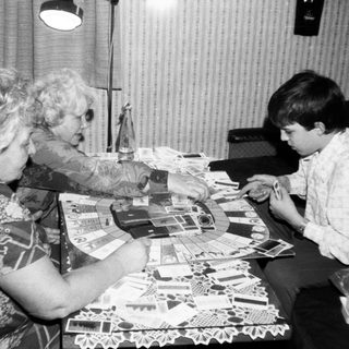 Two women and a boy crafting with paper cutouts.