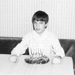 Young boy sitting at table with birthday cake.