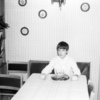 Young boy sitting at table with birthday cake.