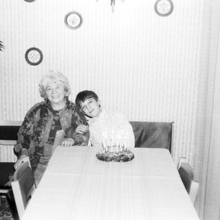 A woman and young boy posing indoors near a birthday cake.