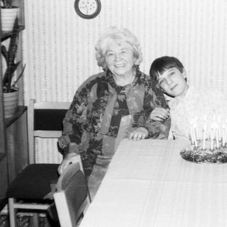 A woman and young boy posing indoors near a birthday cake.