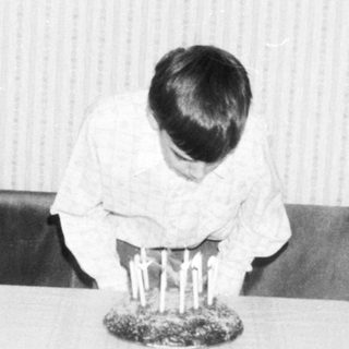 Child sitting at table during indoor ceremony.