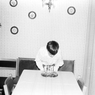 Child sitting at table during indoor ceremony.