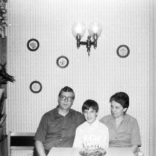 Family celebrating a birthday with cake indoors.