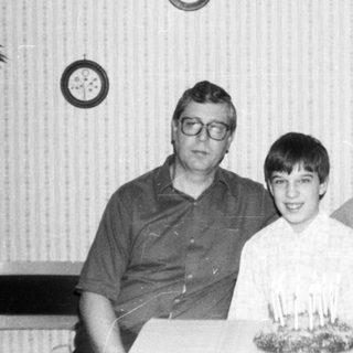 Family celebrating a birthday with cake indoors.