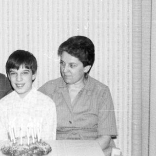 Family celebrating a birthday with cake indoors.