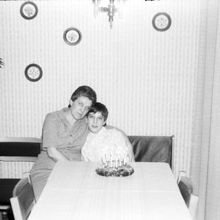Two people posing together indoors at a table.