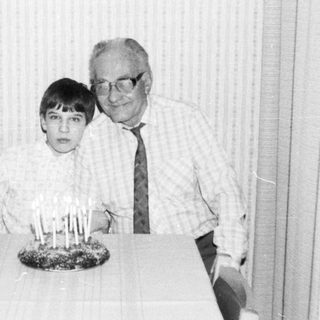 A man and a young boy at a birthday table with candles.