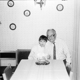 A man and a young boy at a birthday table with candles.