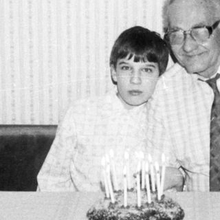 A man and a young boy at a birthday table with candles.