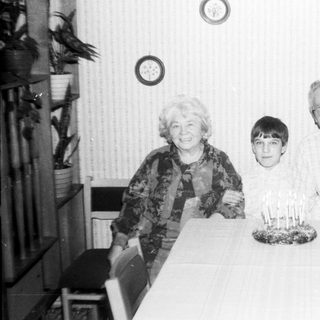 Family celebrating a birthday with candles on cake.