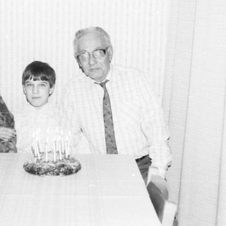 Family celebrating a birthday with candles on cake.