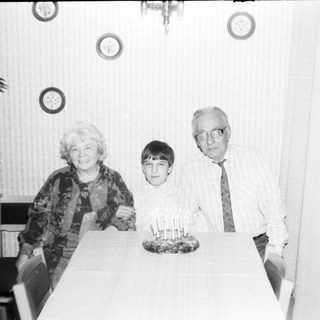 Family celebrating a birthday with candles on cake.