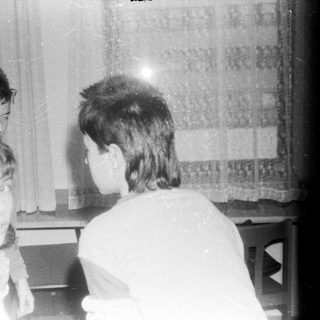 Four children gathered indoors, focused on a screen.