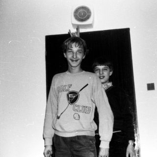Two boys wearing golf sweatshirts posing indoors.