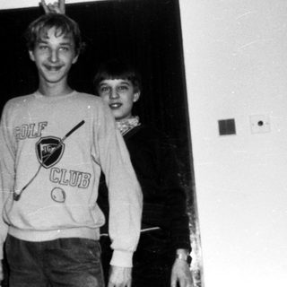 Two boys wearing golf sweatshirts posing indoors.