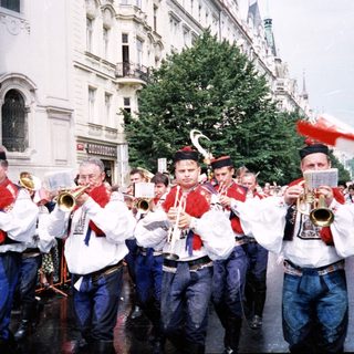 Band in traditional uniforms playing outdoors during parade.