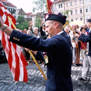 Military veterans parade with flags in public.