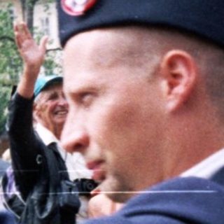 Military veterans parade with flags in public.