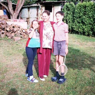 Family posing outdoors with tennis rackets.