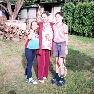 Family posing outdoors with tennis rackets.