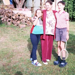 Family posing outdoors with tennis rackets.